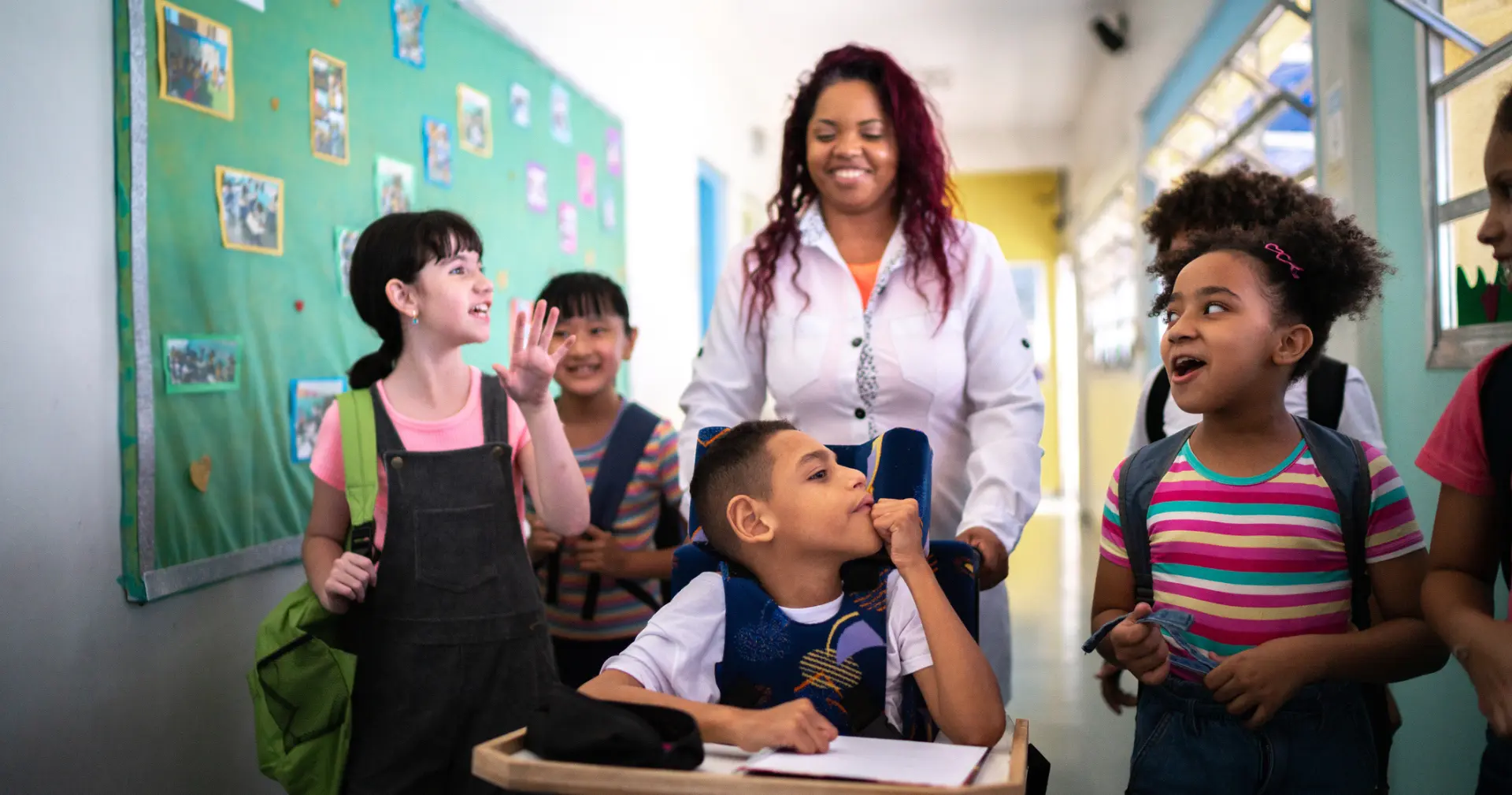 Teacher and students walking in the corridor at school - including a person with special needs